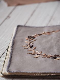 a close up of a piece of cloth on a wooden floor with embroidered flowers and leaves