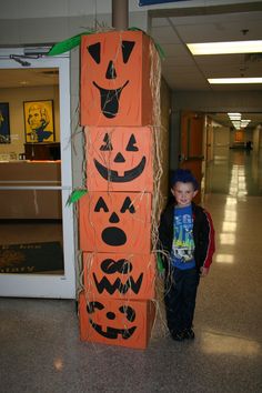 a young boy standing next to a cardboard halloween sign