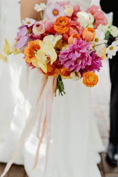 a bride holding a bouquet of flowers in her hand and standing next to the groom