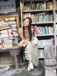 a woman sitting on a bench in front of a bookshelf filled with books