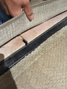 a person is touching the edge of a rug with their hand and foot on it