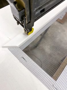 a piece of metal being worked on by a machine that is cutting through the mesh