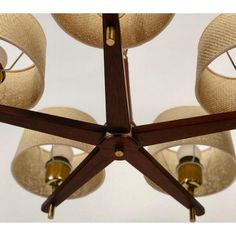 a wooden chandelier with four lamps hanging from it's sides and three shades of beige