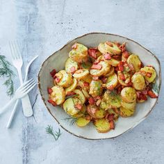 a white bowl filled with cooked potatoes and garnished with herbs