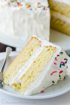 a slice of cake with white frosting and sprinkles on a plate