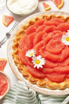 a pie with flowers on it sitting on a table next to other plates and utensils