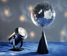 a disco ball sitting on top of a table next to a black stand with a light