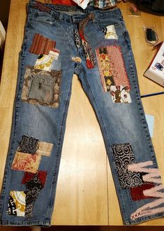 a pair of blue jeans with patchwork on them sitting on top of a wooden floor