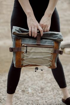 "The Denver Roll Top has it all; ample space and storage, ultimate comfort and multiple carrying options. This bag, made from waxed canvas, leather and waterproof ripstop, features cushioned hip flaps to wear around your waist or across your chest/back. It comes with a detachable, adjustable wide webbing strap to wear the bag crossbody or over the shoulder. The large front zipper pocket features shock cording to carry any additional items, like a layering shirt for hiking or a pair of gloves. Attach a carabiner to the cording and bring along doggie bags on your walk. Ripstop lining is waterproof, lightweight and super durable. Inside, you'll find two slip pockets. The Denver Roll Top has a leather base for added durability. Dimensions: 15\" wide 13.5\" tall (unrolled) 9.5\" tall (rolled) 3 Rugged Waxed Canvas Bag For Outdoor Activities, Outdoor Leather Camera Bag With Adjustable Strap, Leather Camera Bag With Adjustable Strap For Outdoor, Outdoor Shoulder Bag In Coated Canvas With Waxed Finish, Functional Leather Belt Bag For Outdoor, Leather Shoulder Bag With Waxed Finish For Outdoor, Outdoor Waxed Canvas Shoulder Bag With Zipper Pocket, Leather Crossbody Belt Bag For Outdoor, Outdoor Waxed Finish Crossbody Shoulder Bag