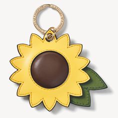 a leather key chain with a sunflower on the front and green leaves on the back