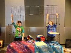 two children are standing behind a table with luggage on it and one boy is holding his hands up