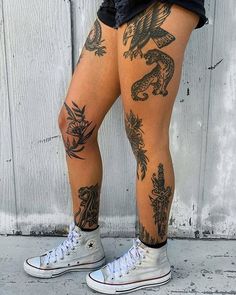 a person with tattoos on their legs standing next to a white wall and wearing black shorts