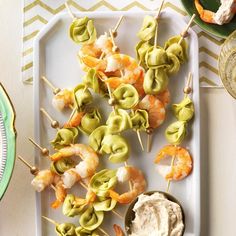 shrimp and olive skewers on a plate with dip