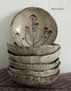 a stack of ceramic bowls with flowers painted on the front and side, sitting on a table