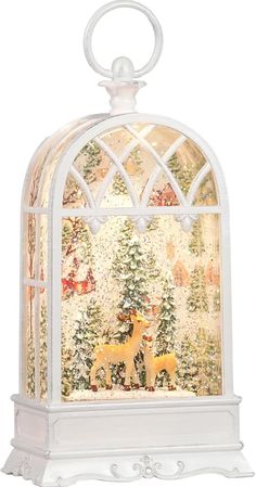 a lighted christmas scene in a white birdcage with deers and trees on it