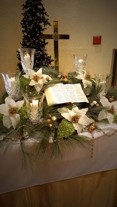 a table topped with flowers and an open book next to a cross on top of it