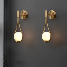 two lights on the wall next to each other in a room with dark walls and flooring