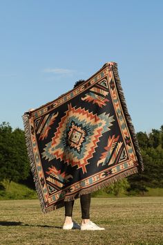 a person standing in the grass holding up a blanket