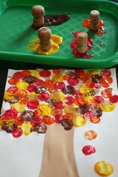 a child's hand is painting a tree with gummy bears on the paper