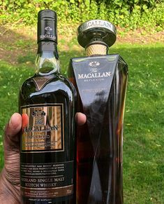 a hand holding up a bottle of macallan and another bottle in the background