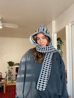 a woman wearing a hat and scarf standing in a living room with a ceiling fan