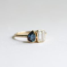 two gold rings with blue and white stones on them, one is in the shape of a tear