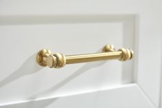 a gold handle on a white cabinet door