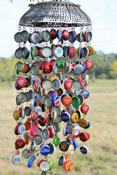 the bottle cap wind chime is hanging in front of an open field with trees