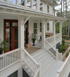 a white house with stairs leading up to the front door and second story porch area