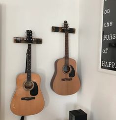 two guitars are hanging on the wall next to each other with crosses attached to them