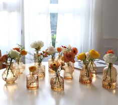 there are many vases with flowers in them sitting on the table next to each other