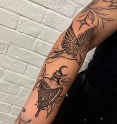 a person with a tattoo on their arm holding a bottle and two birds flying over it