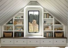 an attic bedroom with built in bookshelves and storage space underneath the roof window