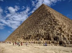 the great pyramid in giza, egypt with people walking around it and clouds overhead