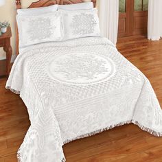 a bed with white bedspread and pillows on top of it in a room