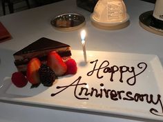 a piece of cake with a candle on it and strawberries in the foreground