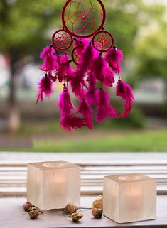 a pink dream catcher sitting on top of a window sill next to two rocks