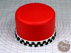 a red and black cake sitting on top of a white table next to a ruler