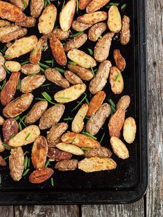 roasted peanuts on a baking sheet ready to be cooked in the oven with green garnishes