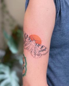 a woman with a tattoo on her arm and an orange circle in the middle of her arm