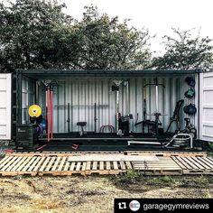 a storage container with lots of equipment in it's back yard, surrounded by trees