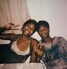 two young women posing for a photo in front of a white curtain with their fingers up