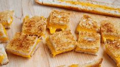 several pieces of toasted cheese sandwich sitting on a cutting board next to two slices of bread