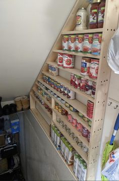 an organized pantry under the stairs in a loft space with shelves full of canned food