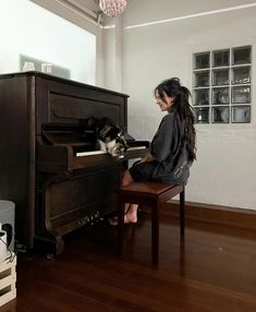 a woman sitting at a piano with her dog