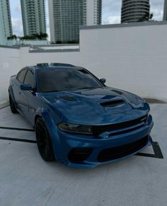 a blue dodge charger parked in front of some tall buildings