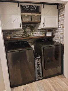 a washer and dryer in a laundry room with white cabinets, wood flooring and brick wall