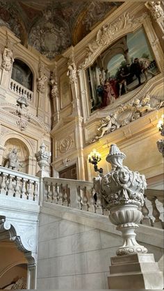 an ornate staircase in a building with paintings on the walls