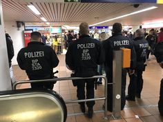 two police officers are walking through the airport terminal with their backs turned to the camera