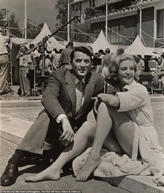 a man and woman sitting next to each other in front of a swimming pool with tents